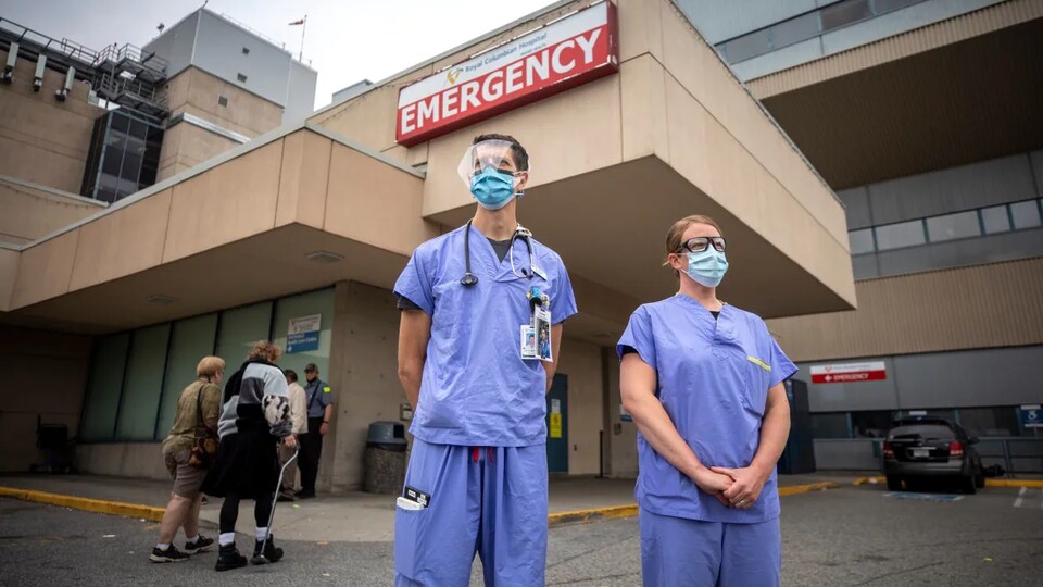 Deux personnes en uniforme médical devant le service d'urgence.