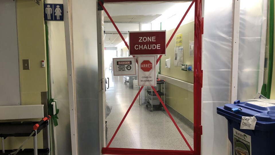 Une porte où on peut lire « zone chaude » à l'entrée d'une zone COVID-19.