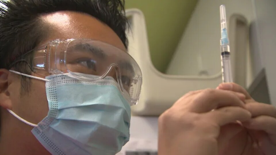 Un professionnel de la santé manipule une seringue.