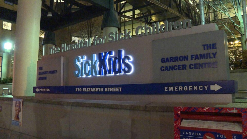 Enseigne lumineuse devant un bâtiment qui indique le nom de l'hôpital ainsi que différentes directions