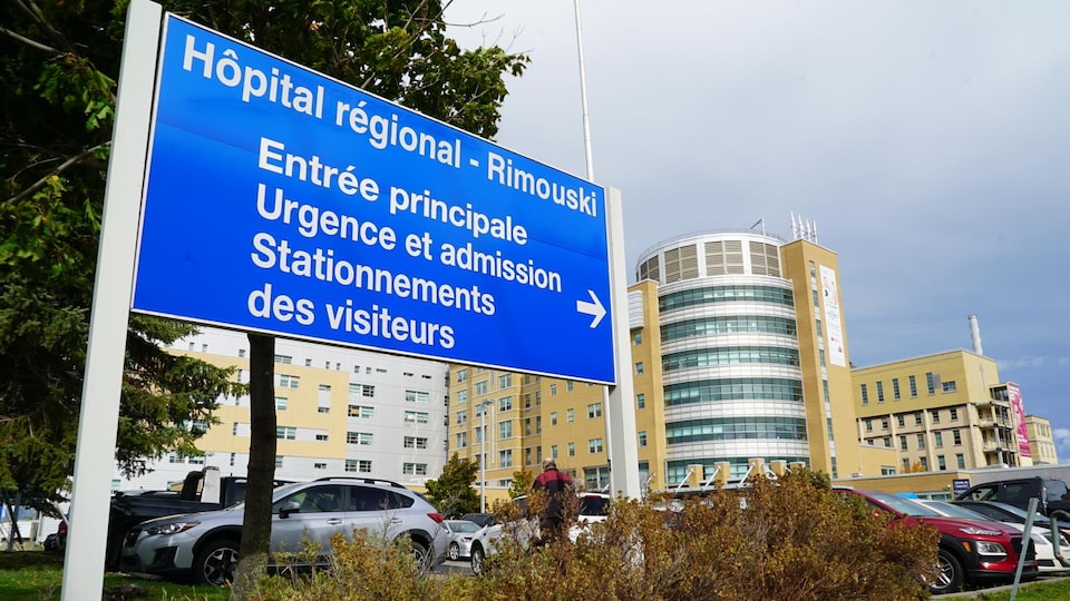 Une affiche à l'entrée du stationnement indique l'entrée principale, l'urgence et l'admission ainsi que le stationnement des visiteurs de l'hôpital.