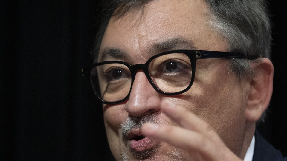 Gros plan sur M. Arruda, qui porte des lunettes.