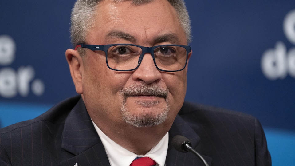 Horacio Arruda écoute, le visage dur et fermé, lors d'une conférence de presse.