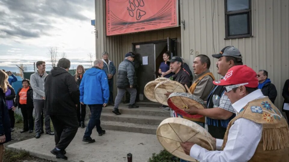 John Horgan entre dans le bâtiment entouré de personnes autochtones qui jouent du tambour.