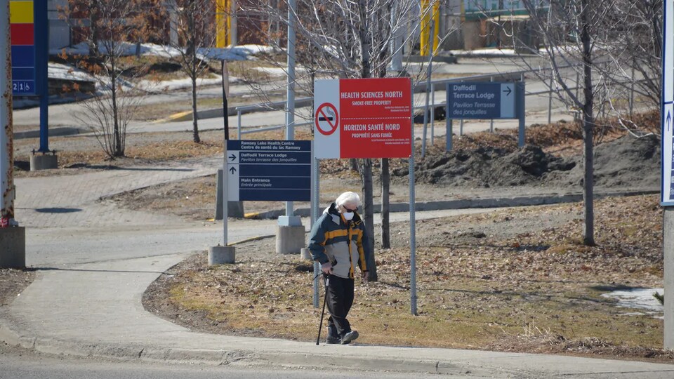 Un homme portant un masque marche près de l'hôpital Horizon Santé-Nord.