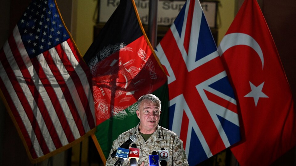 Le général McKenzie devant des drapeaux américain, afghan, anglais, et turque.