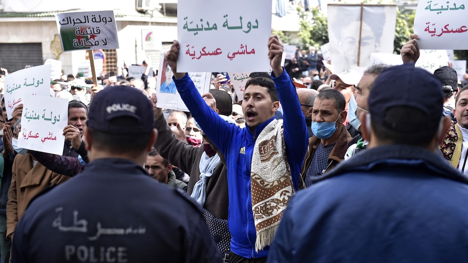 Des manifestants portant des pancartes face à des policiers.