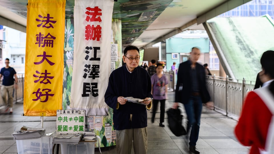 Un membre du mouvement Falun Gong offre aux passants des exemplaires du journal anti-communiste Epoch Times dans les rues de Hong Kong.