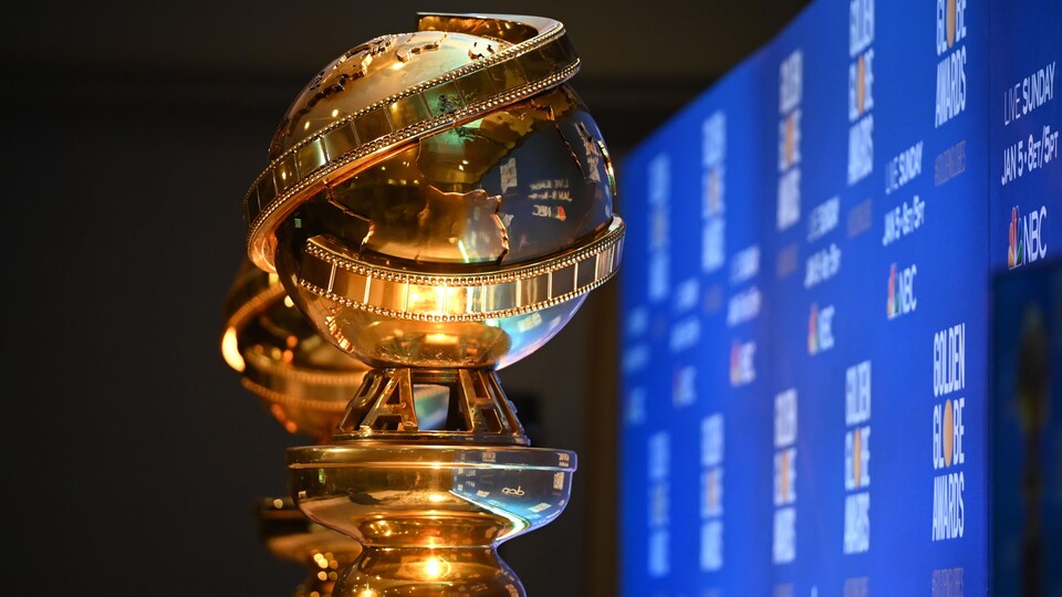 Deux trophées Golden Globes vus de près, devant un écran bleu.