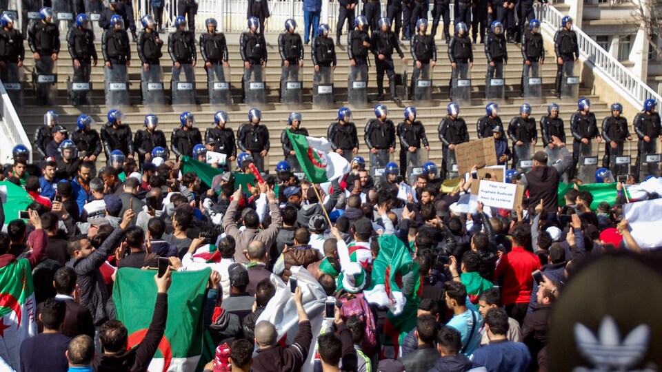 Des manifestants devant un bâtiment officiel gardé par la police, en Algérie