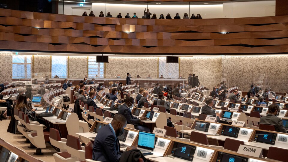 Des délégués sont assis derrière des écrans pour une conférence d'examen des Nations unies.