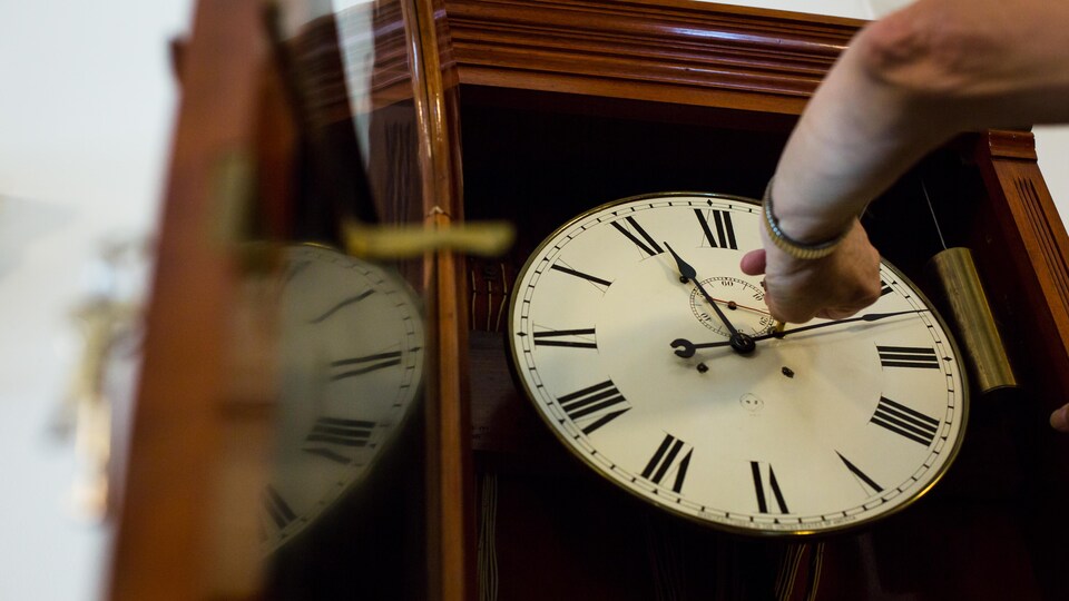 André Viger tourne une clé dans une horloge de l'Assemblée nationale afin de la remonter.