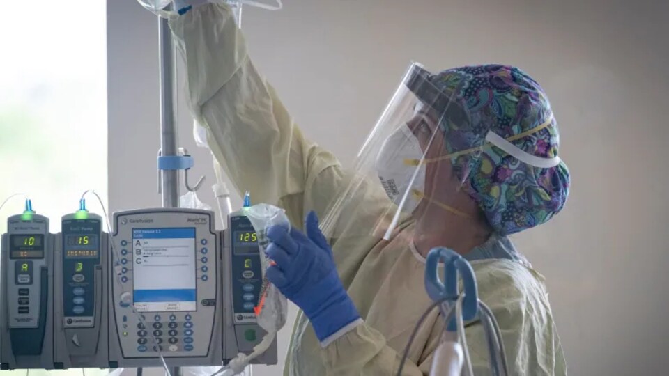 Une employée des services médicaux porte un masque N95 et une visière au travail dans un hôpital albertain.