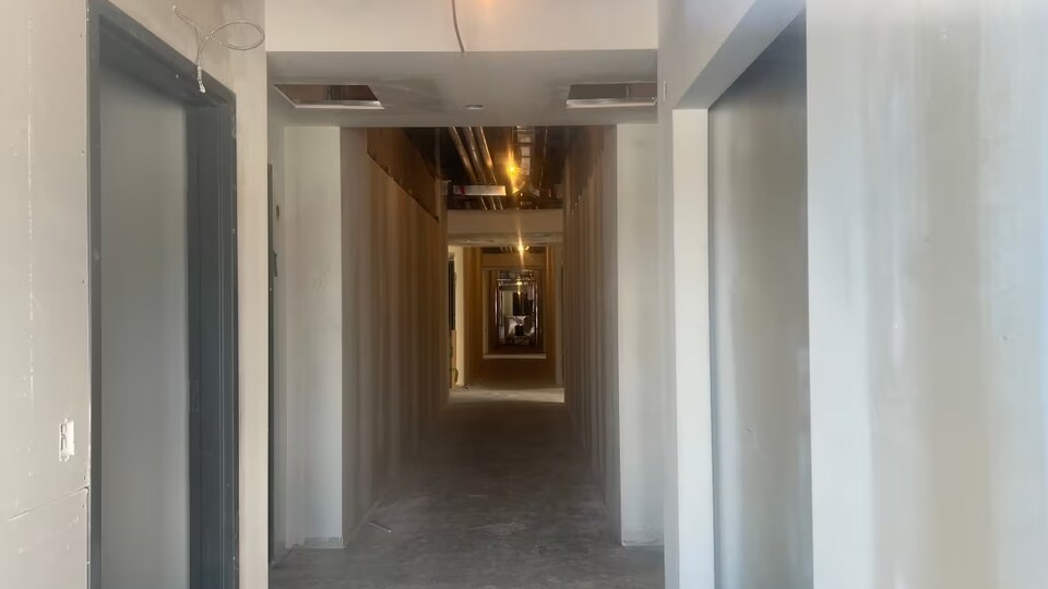 Un couloir avec des câbles qui sortent des murs et des planchers de ciment.