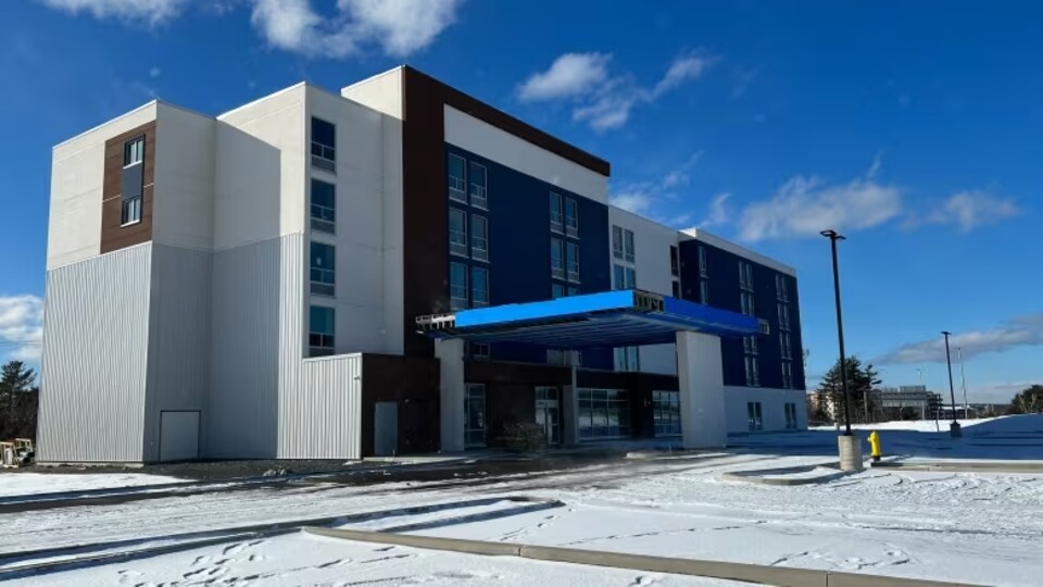 Un hôtel brun et blanc et un stationnement désert.