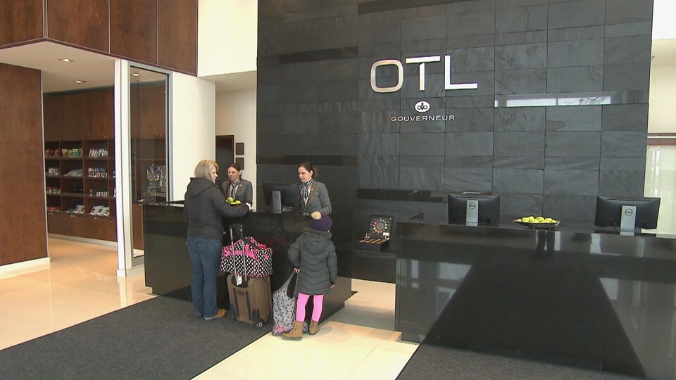 Le hall de l'hôtel Gouverneur avec une employé qui parle avec un client.