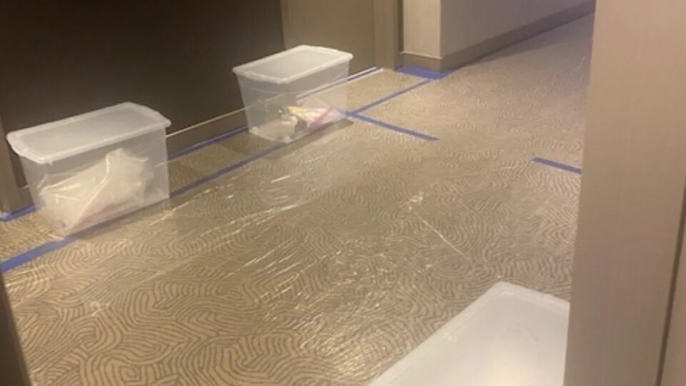 Des planchers recouverts de plastique et des boites de plastique posées devant des portes de chambres.