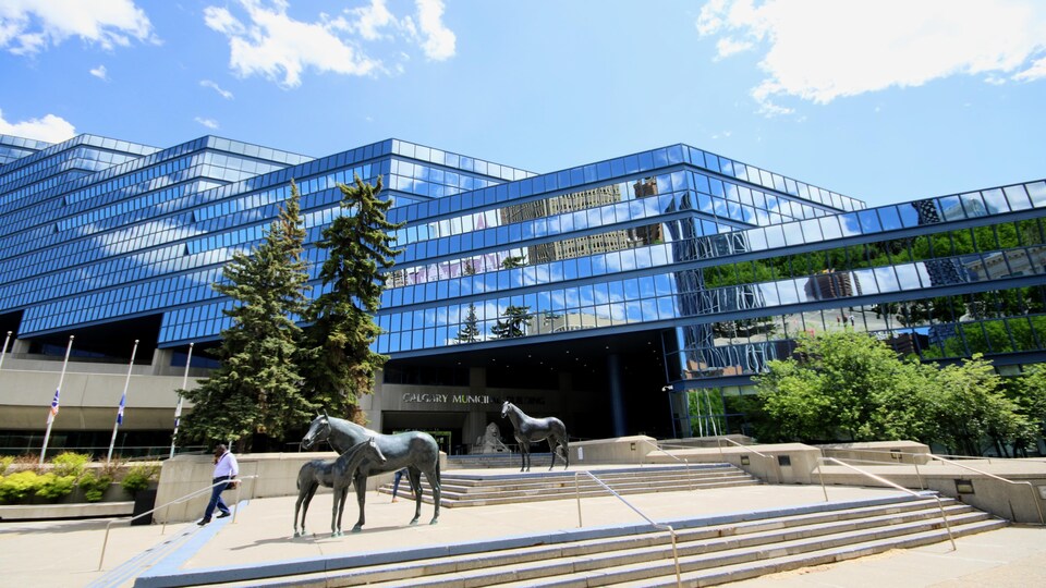 Sculptures de chevaux en métal avec un bâtiment vitré.