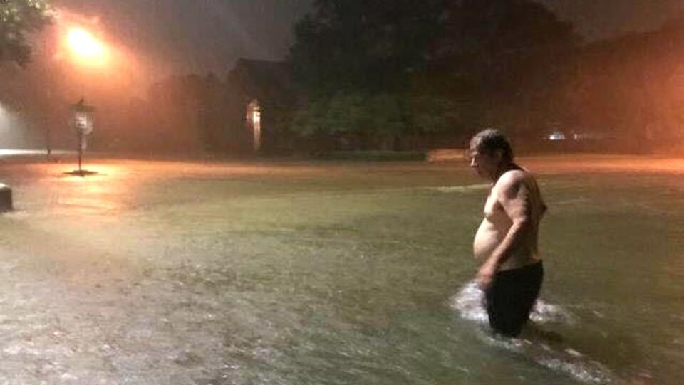 Un homme du secteur Clear Lake de Houston au Texas se promène dans la rue inondée de son quartier.