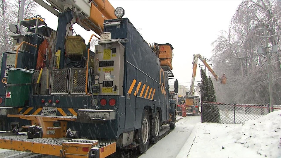 Deux camions d'Hydro-Québec et une nacelle déployée près des fils électriques.
