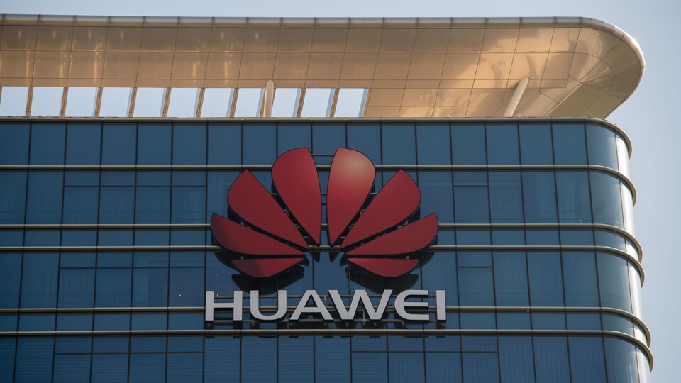 Gros plan sur le logo de Huawei sur la façade d'un gratte-ciel vitré.