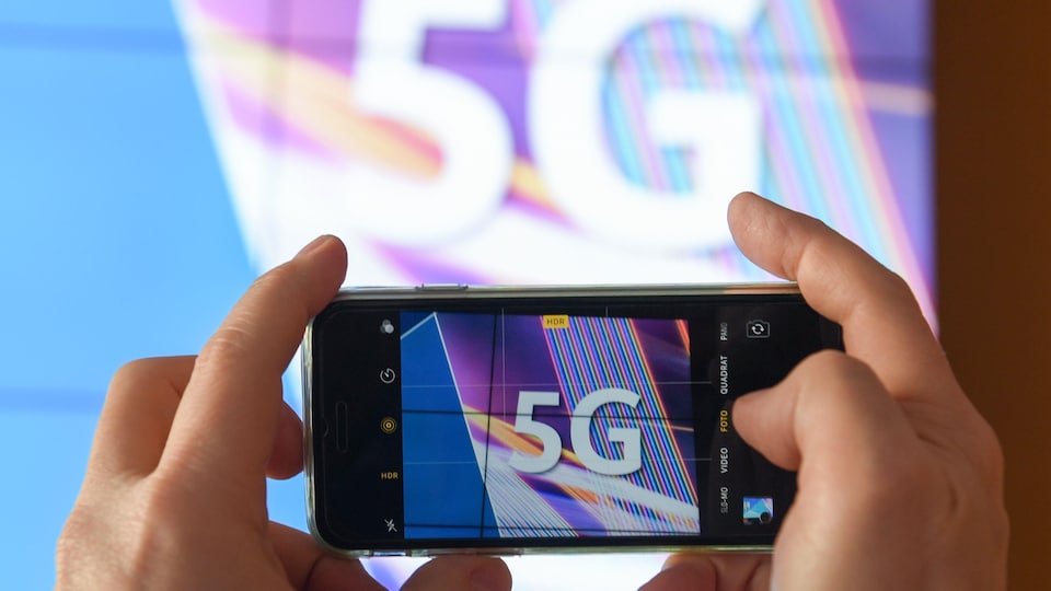 Vue d'un écran de téléphone prenant en photo une projection avec la mention 5G.