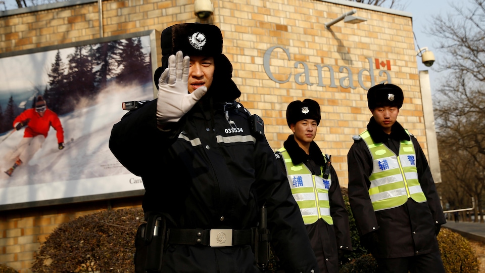 Des policiers montent la garde devant l'ambassade du Canada à Pékin.