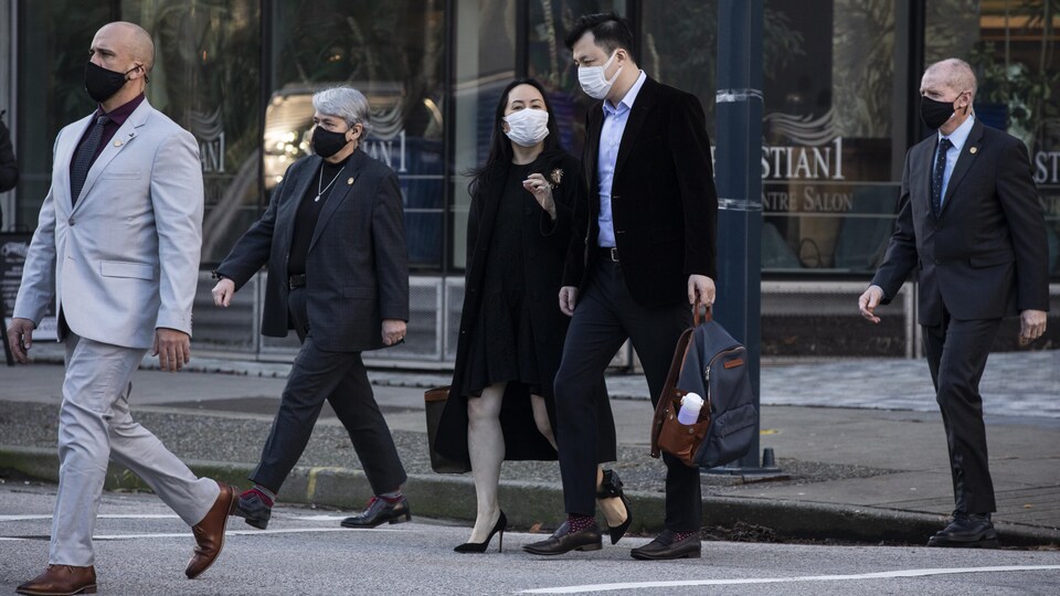 Meng Wanzhou et son mari entourés de gardes du corps.