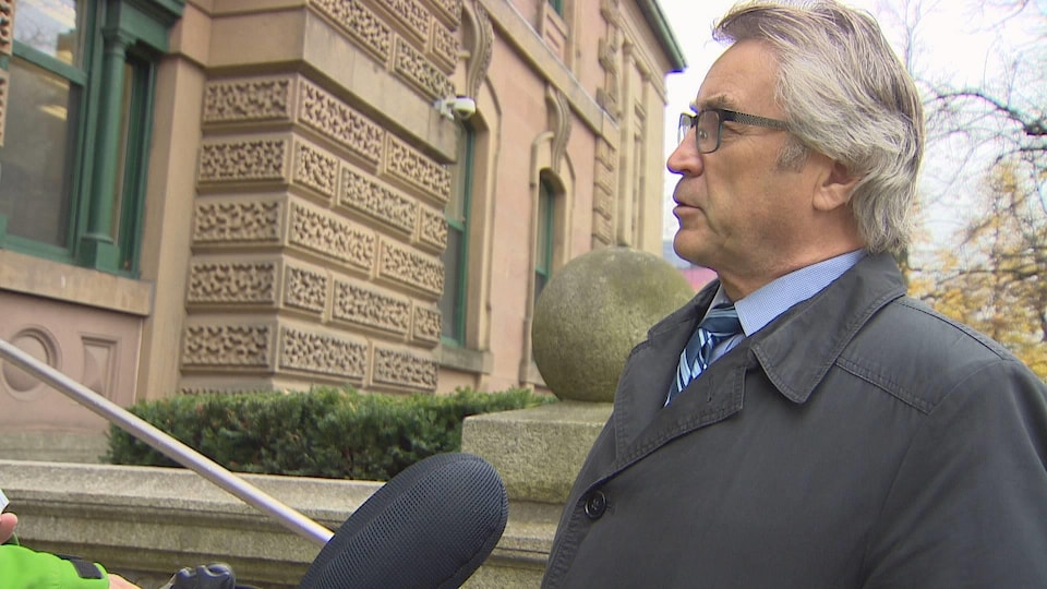 Un homme donne une entrevue au micro devant le palais de justice.