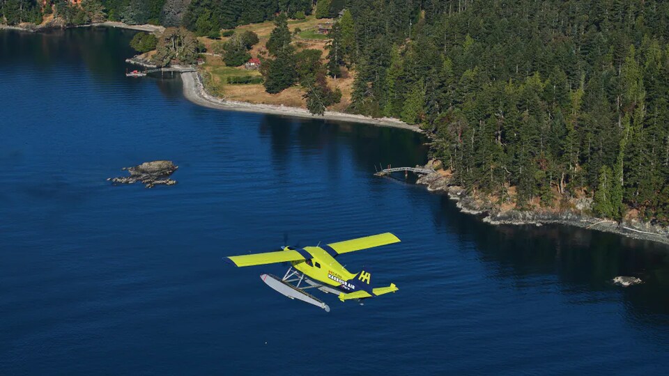 Un hydravion électrique de Harbour Air Seaplanes survole un plan d'eau en Colombie-Britannique.