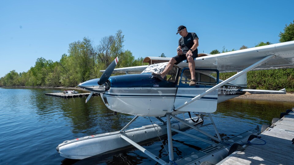 Un homme est posé sur un hydravion qui flotte sur l'eau.