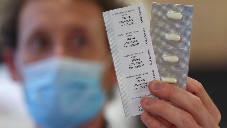 Un employé de pharmacie tient des comprimés d'hydroxychloroquine.