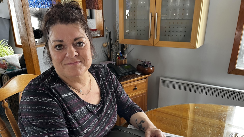 LeBlanc sitting at her wooden kitchen table.  His hands are resting on the purchase and warranty documents for his car. 