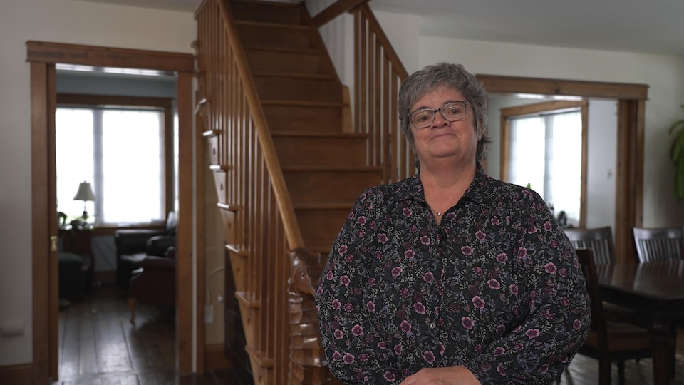 Sarah Martinet stands in front of the interior staircase of her home. 