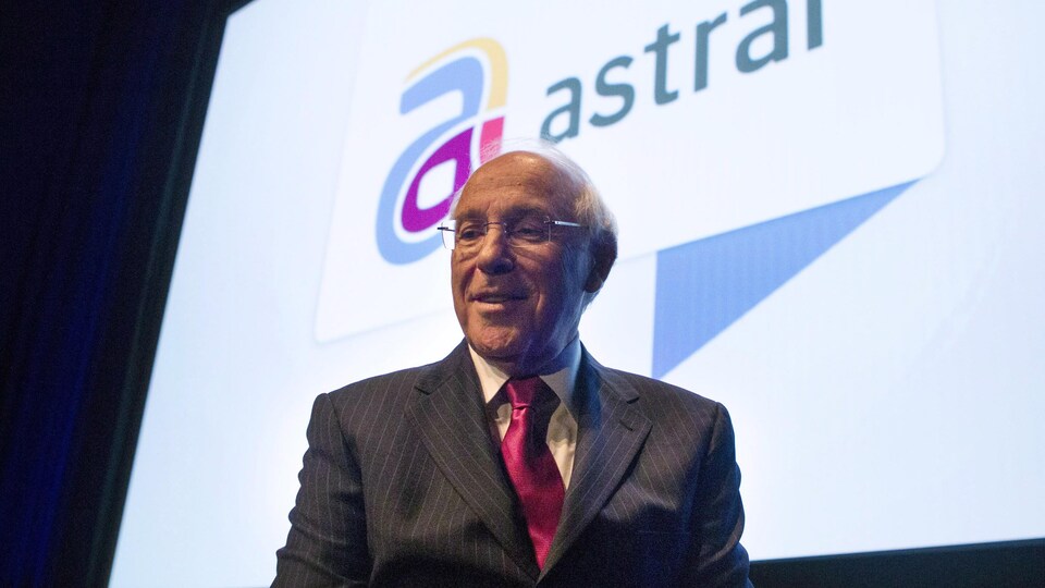 Portrait de Ian Greenberg devant une affiche d'Astral Média