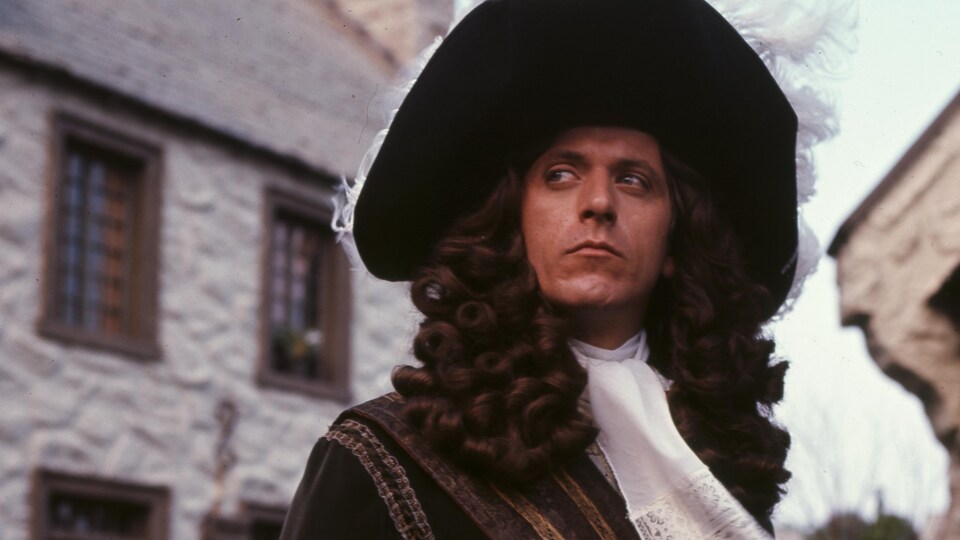 Devant des bâtiments en pierre, Albert Miller dans son rôle de Pierre Le Moyne d'Iberville.