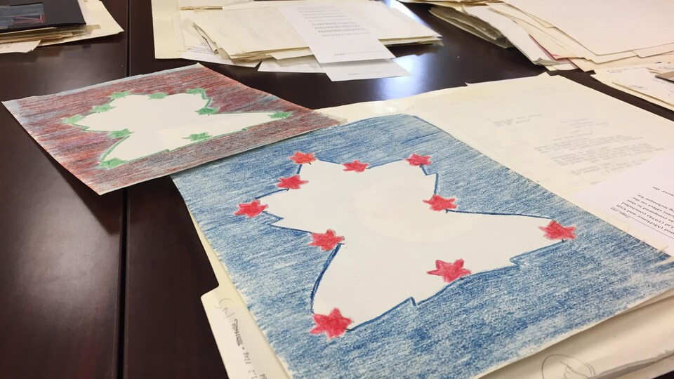 Plusieurs dessins de drapeau du Canada sont entassés sur une table.