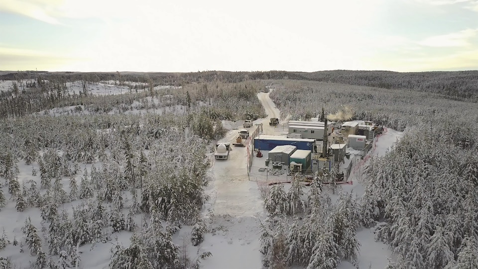 Une photo des lieux vue de haut, prise par un drone. Il y a plusieurs bâtiments au milieu d'une forêt enneigée.