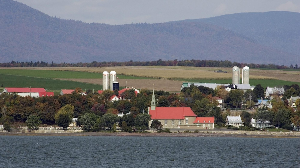 L'île d'Orléans vue de l'autre côté du fleuve, avec l'église Saint-Jean et ses fermes.