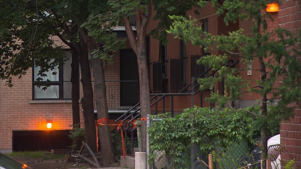 L'immeuble où Pierre Coriolan, un homme en crise, a été abattu par le SPVM, dans le quartier Centre-Sud, à Montréal, avec un ruban policier devant une entrée.
