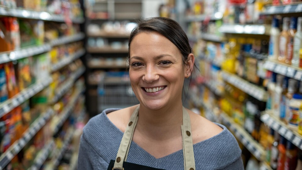 Une commerçante dans une allée de son épicerie.