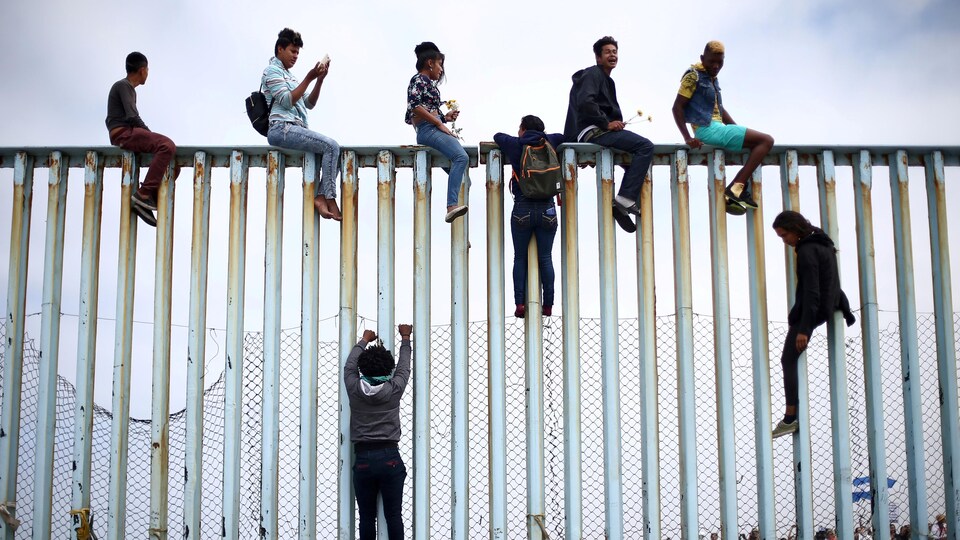 Des Mexicains escaladent une barrière qui sépare le Mexique et les États-Unis en avril 2018.