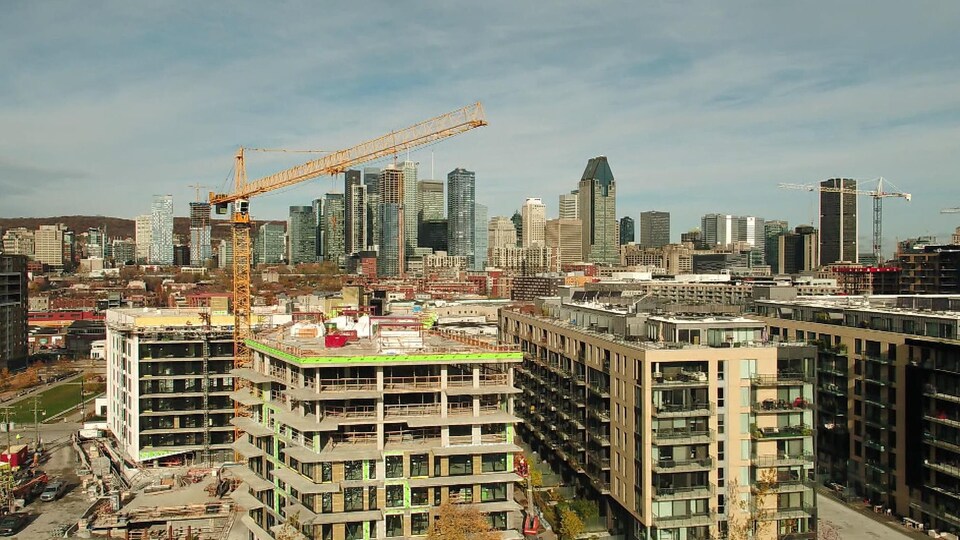 Une grue surplombe un immeuble en construction.