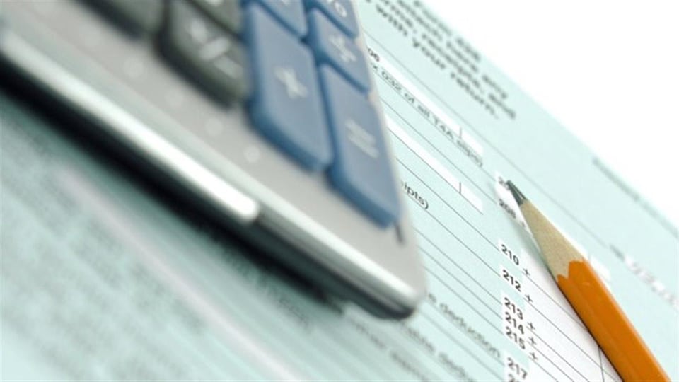 Une calculatrice et un crayon sont sur un formulaire de déclaration de revenus. 
