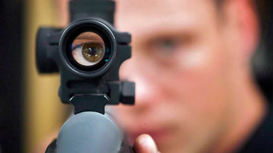 Un homme regarde dans la mire d'un fusil.