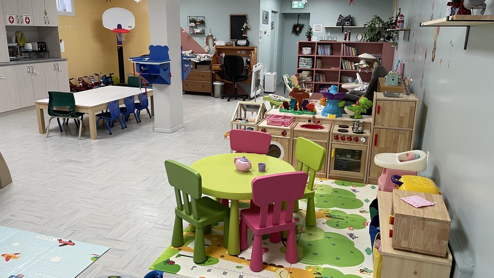 Une salle avec des tables, des jouets pour enfants, une bibliothèque.