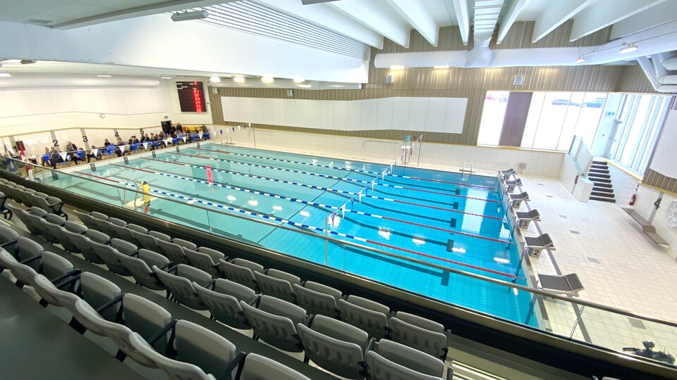 Des gens assis sur des chaises sur le côté de la piscine.