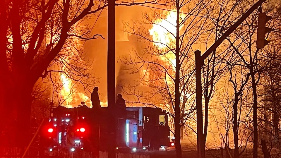 Des pompiers devant une maison en feu. 