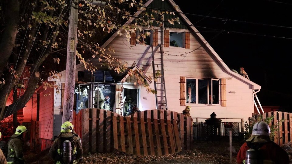 Des pompiers devant et dans une résidence qui vient de brûler.