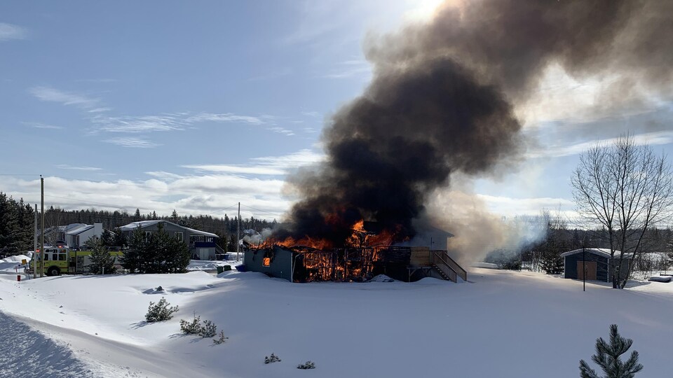 Un incendie majeur dans une maison dont s'échappe un épais panache de fumée.